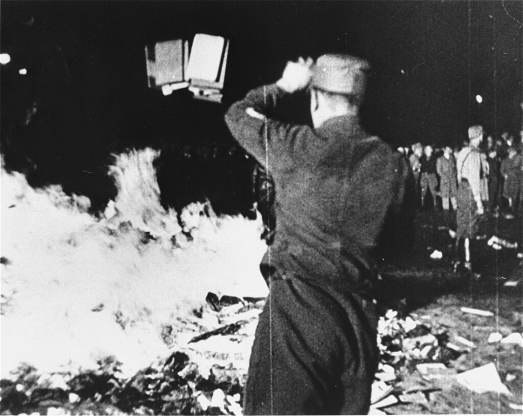 A member of the SA throws confiscated books into the bonfire during the public burning of "un-German" books on the Opernplatz in Berlin. (US Holocaust Museum, Public Domain)